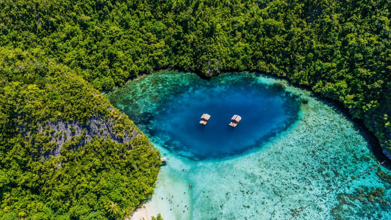 Stunning aerial shot of a vibrant blue lagoon surrounded by lush greenery in Caraga, Philippines.