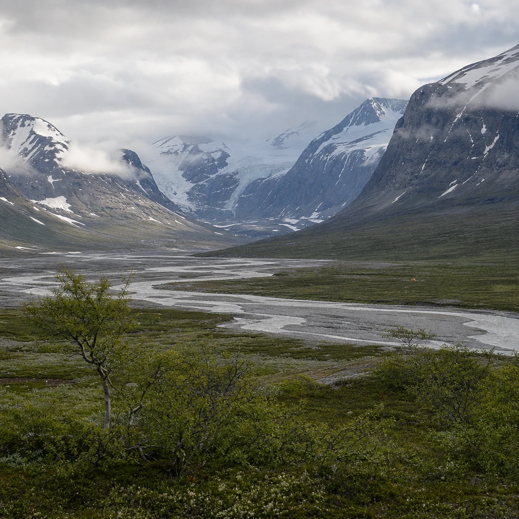 Wide Arctic mountain valley with a braided glacial river, glaciers on snow-streaked peaks and low cloud